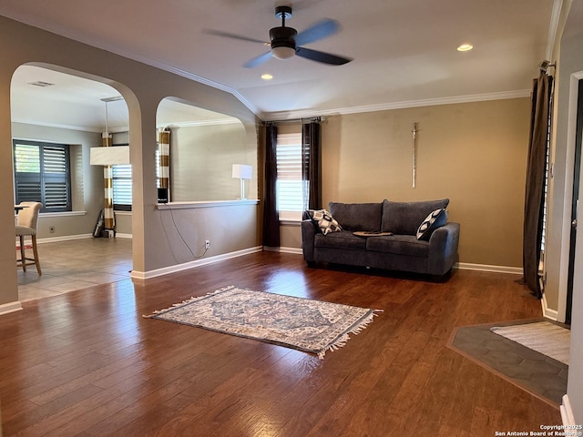 living room featuring ceiling fan, a healthy amount of sunlight, wood-type flooring, and ornamental molding