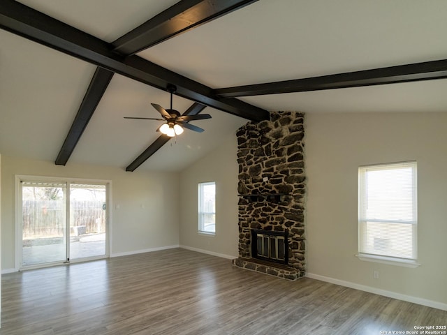 unfurnished living room featuring ceiling fan, a fireplace, lofted ceiling with beams, and light wood-type flooring