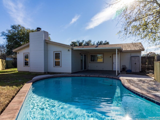 rear view of property featuring a fenced in pool