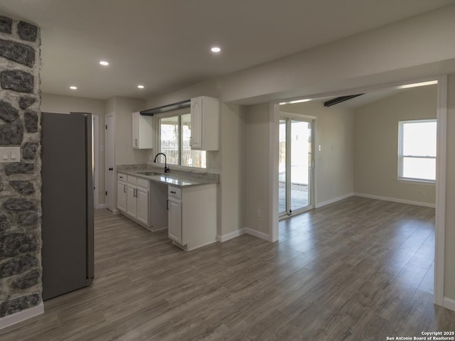 kitchen featuring white cabinets, hardwood / wood-style flooring, sink, and stainless steel refrigerator