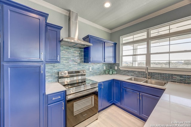 kitchen featuring sink, wall chimney exhaust hood, stainless steel range with electric stovetop, and blue cabinets