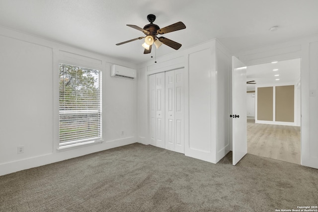 unfurnished bedroom with a wall mounted air conditioner, ceiling fan, carpet floors, and a closet