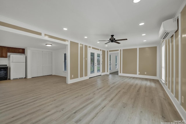 unfurnished living room with french doors, ceiling fan, an AC wall unit, light hardwood / wood-style floors, and plenty of natural light