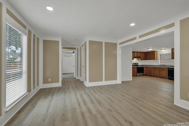 unfurnished living room with ceiling fan, light hardwood / wood-style floors, and sink