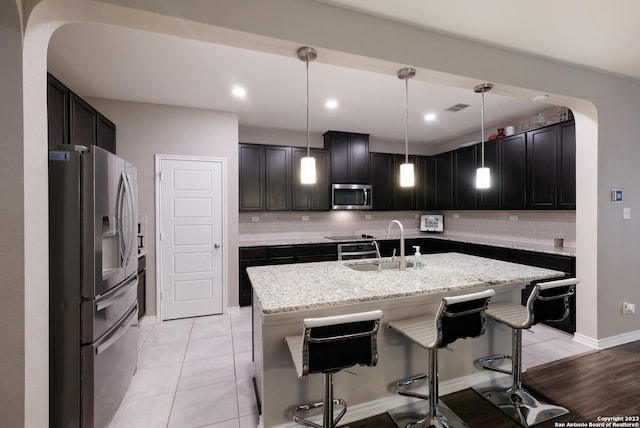 kitchen with stainless steel appliances, visible vents, hanging light fixtures, a kitchen island with sink, and a sink