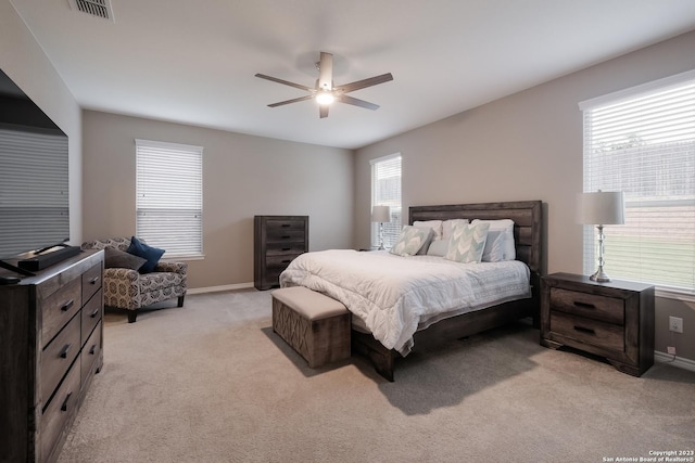 bedroom with light colored carpet, ceiling fan, visible vents, and baseboards