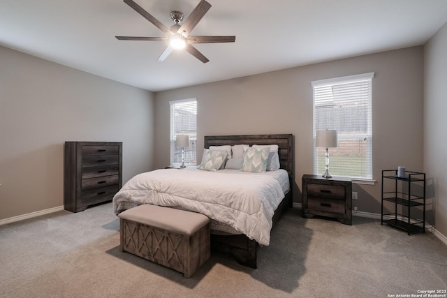 bedroom with light carpet, ceiling fan, baseboards, and multiple windows