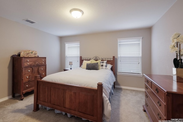 bedroom with baseboards, visible vents, and light colored carpet