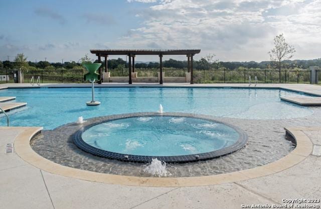 view of swimming pool with fence, a pool with connected hot tub, and a pergola