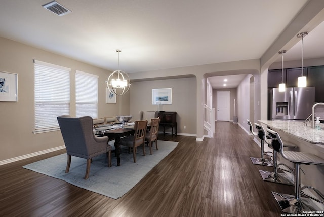 dining room featuring baseboards, visible vents, arched walkways, dark wood-style flooring, and a notable chandelier