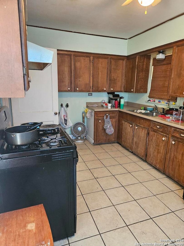 kitchen featuring black gas range, light tile patterned floors, exhaust hood, and sink