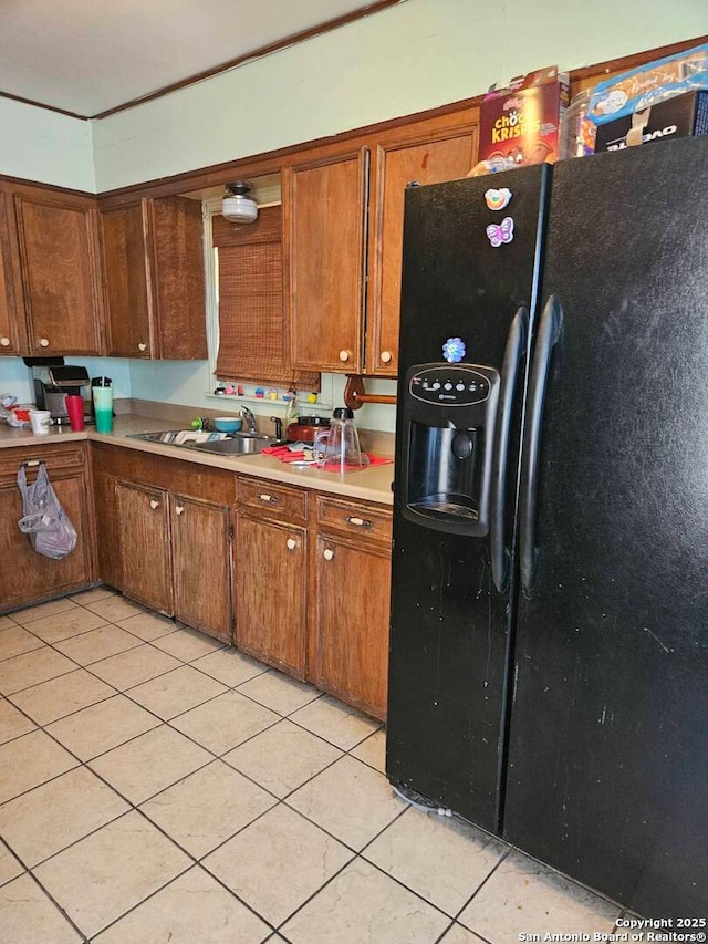 kitchen featuring black fridge, sink, and light tile patterned floors