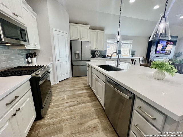 kitchen with appliances with stainless steel finishes, light hardwood / wood-style flooring, white cabinetry, and sink