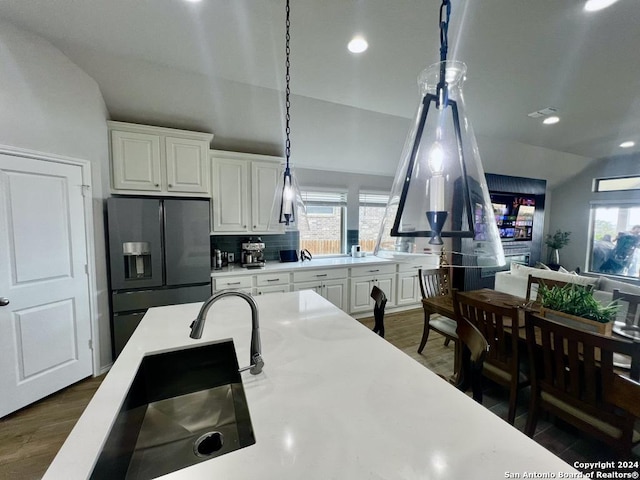 kitchen featuring decorative backsplash, black fridge, white cabinetry, hanging light fixtures, and lofted ceiling