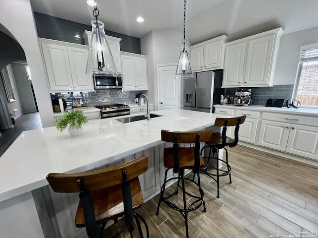 kitchen featuring white cabinetry, sink, hanging light fixtures, and appliances with stainless steel finishes