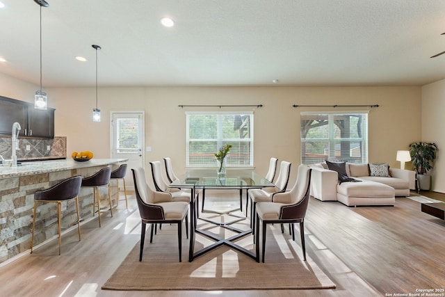 dining area featuring a textured ceiling, light hardwood / wood-style floors, and a healthy amount of sunlight