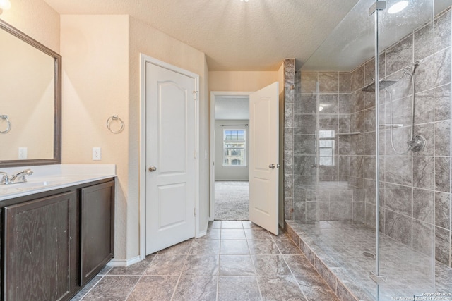 bathroom with a tile shower, vanity, and a textured ceiling