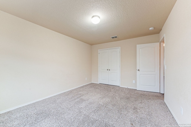 unfurnished bedroom featuring light carpet, a closet, and a textured ceiling