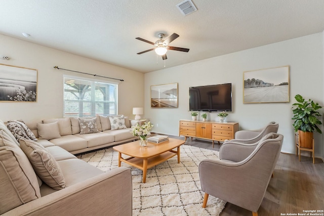 living room with ceiling fan, a textured ceiling, and light wood-type flooring