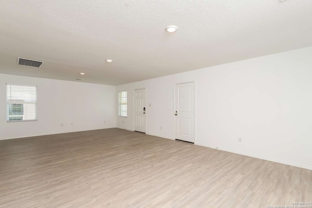 unfurnished room with light hardwood / wood-style floors and a textured ceiling