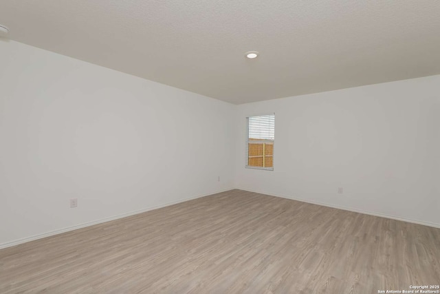 empty room featuring a textured ceiling and light hardwood / wood-style flooring