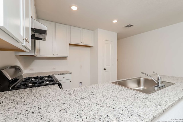 kitchen with gas stove, sink, light stone counters, white cabinets, and exhaust hood