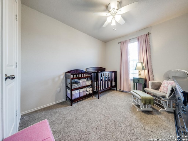 bedroom with ceiling fan, a crib, and carpet flooring