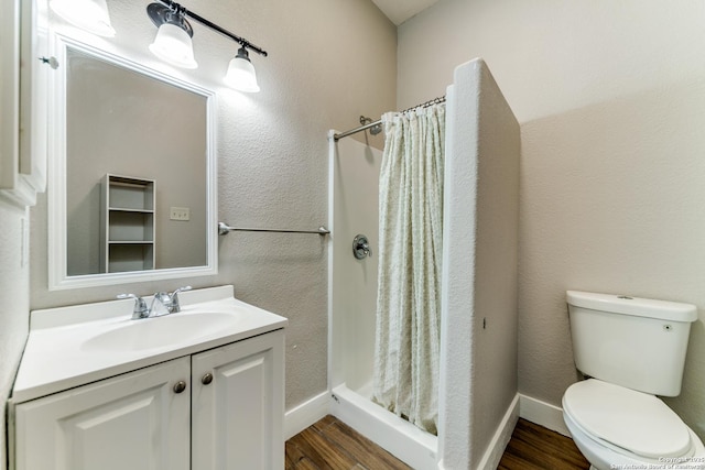 bathroom featuring a shower with shower curtain, hardwood / wood-style flooring, vanity, and toilet