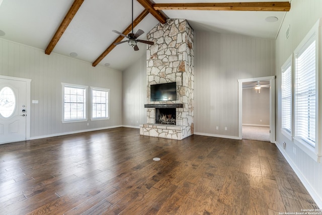 unfurnished living room with dark hardwood / wood-style floors, ceiling fan, beamed ceiling, and a stone fireplace