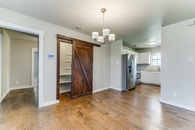 kitchen featuring a barn door, stainless steel appliances, a textured ceiling, white cabinets, and sink