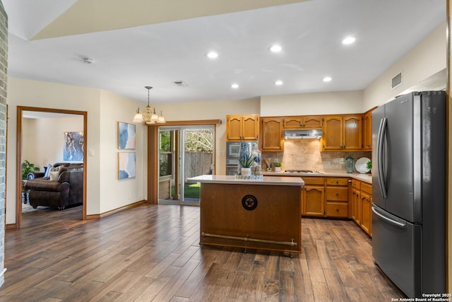 kitchen with dark wood-type flooring, stainless steel appliances, a center island, and hanging light fixtures