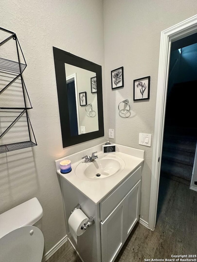 bathroom featuring vanity, wood-type flooring, and toilet