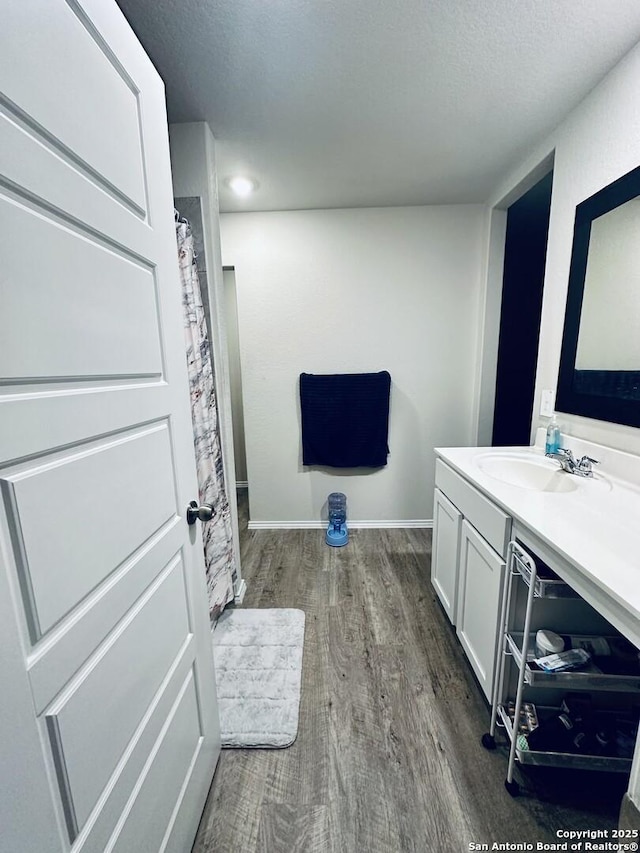 bathroom featuring wood-type flooring, vanity, a textured ceiling, and curtained shower