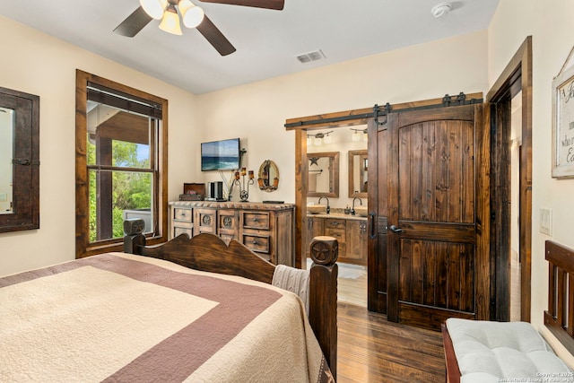 bedroom with ceiling fan, a barn door, and hardwood / wood-style floors