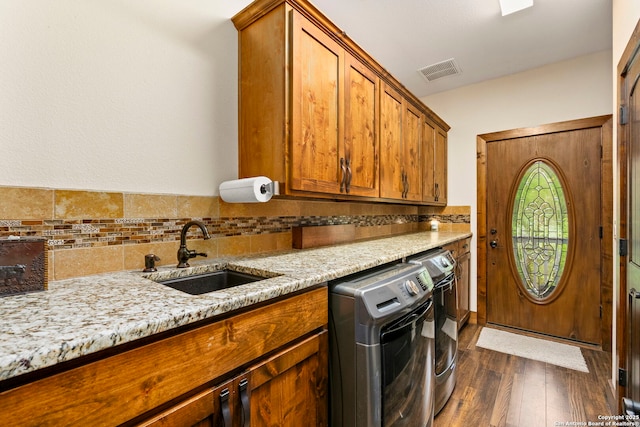 laundry area featuring sink, cabinets, dark hardwood / wood-style flooring, and washing machine and clothes dryer