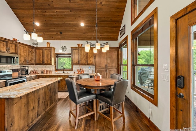 dining room with sink, an inviting chandelier, dark hardwood / wood-style floors, and high vaulted ceiling