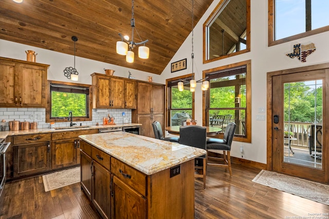 kitchen featuring sink, decorative light fixtures, backsplash, high vaulted ceiling, and a kitchen island