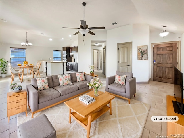 living room with lofted ceiling and ceiling fan with notable chandelier