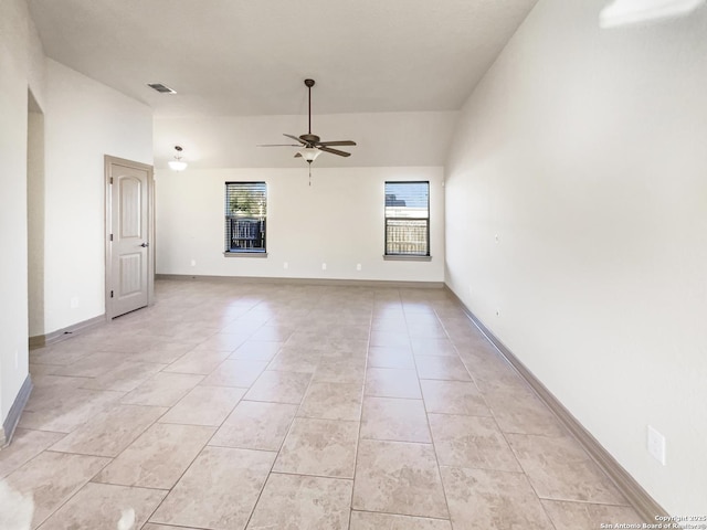 tiled spare room featuring ceiling fan, vaulted ceiling, and plenty of natural light