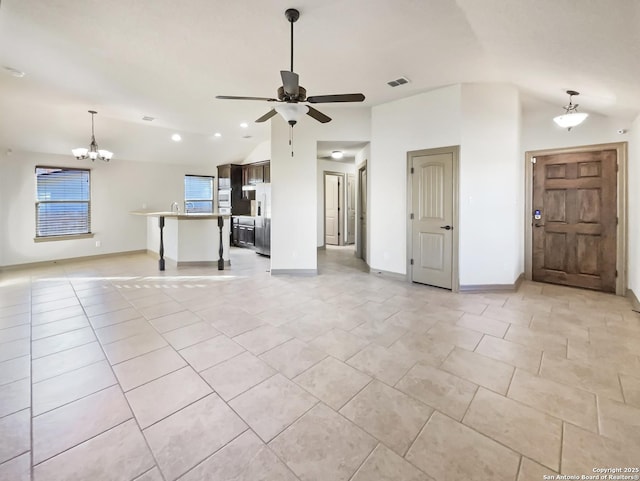 unfurnished living room with lofted ceiling, light tile patterned flooring, and ceiling fan with notable chandelier