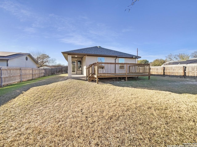 rear view of house featuring a lawn and a deck