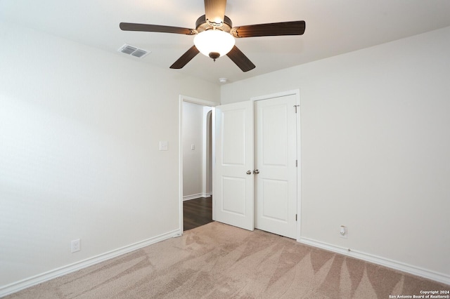 unfurnished bedroom with ceiling fan, a closet, and light colored carpet