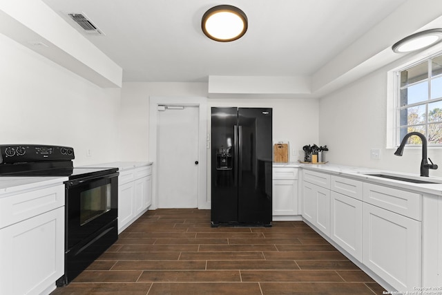 kitchen featuring sink, white cabinetry, and black appliances