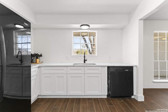 kitchen with light stone countertops, dishwasher, white cabinets, and sink