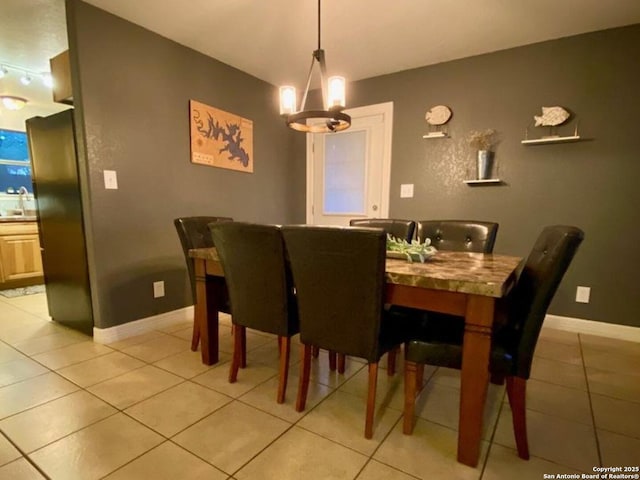 dining room with sink, a chandelier, and light tile patterned floors