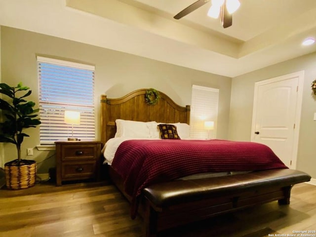 bedroom featuring a raised ceiling, ceiling fan, and hardwood / wood-style flooring