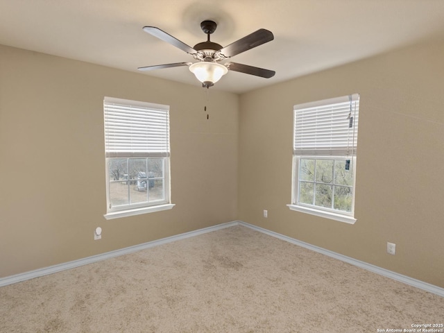 carpeted spare room featuring a wealth of natural light and ceiling fan