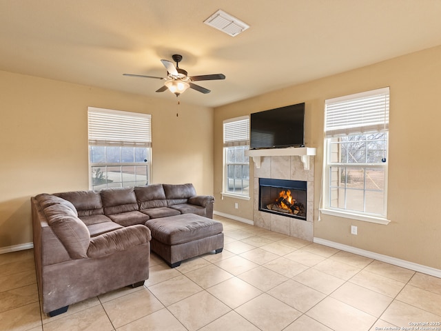 tiled living room with a tile fireplace, a healthy amount of sunlight, and ceiling fan