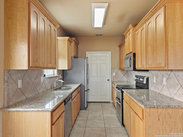 kitchen with appliances with stainless steel finishes, sink, and light brown cabinets