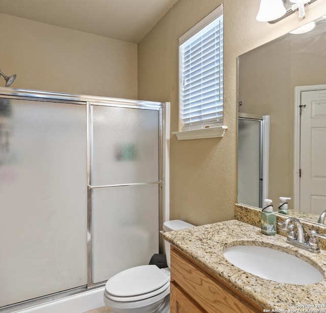 bathroom featuring vanity, toilet, and a shower with shower door